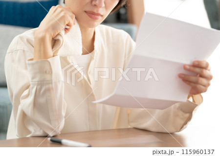手紙を読んで泣く女性 115960137