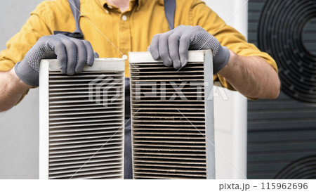 Worker holding two dirty air filters from a home ventilation system. Worker holding two dirty air filters from a home ventilation system. 115962696