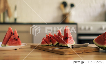 Triangular pieces of watermelon on a wooden cutting board on a kitchen background 115962788