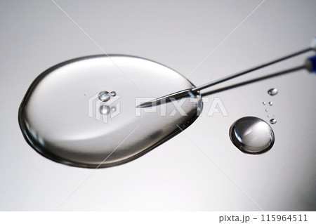 A drop of medicine flowing from a syringe with a needle. 115964511