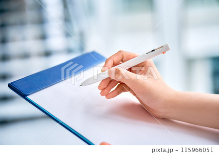 クリップボードに記入する若い女性の手元 115966051