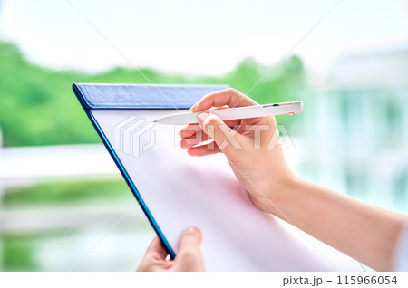 クリップボードに記入する若い女性の手元 115966054