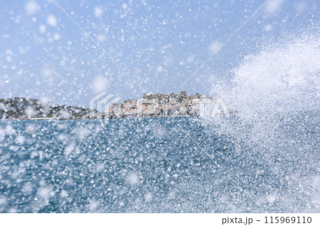 View of the sea with islands in the background and spray from the waves of a speedboat. 115969110