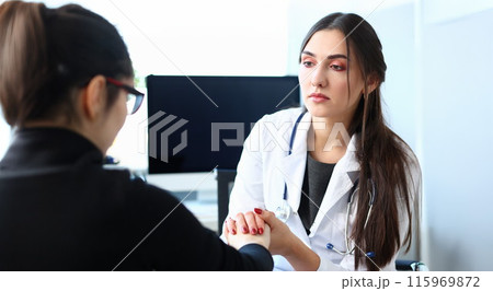 Young female doctor holds sick patient by hand 115969872