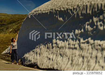 Tourist looking at high snow wall at road, Norway 115970052