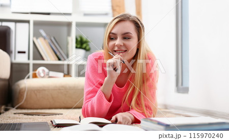 young beautiful blond woman lie on the floor read book 115970240