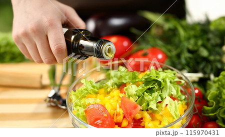 Cook holds bottle in hand and trickles olive Cook holds bottle in hand and trickles olive 115970431