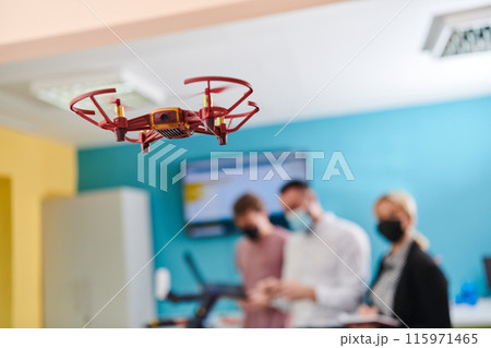 A group of students working together in a laboratory, dedicated to exploring the aerodynamic capabilities of a drone A group of students working together in a laboratory, dedicated to exploring the aerodynamic capabilities of a drone 115971465