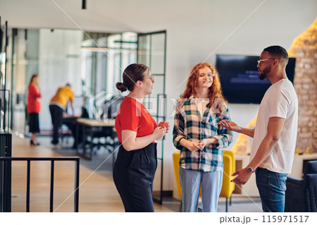 Group of business colleagues, including an African American businessman, engage in a conversation about business issues in the hallway of a modern startup coworking center, exemplifying dynamic Group of business colleagues, including an African American businessman, engage in a conversation about business issues in the hallway of a modern startup coworking center, exemplifying dynamic 115971517