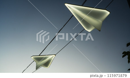 Street lights in the form of paper airplanes, against the background of the sunset sky 115971879