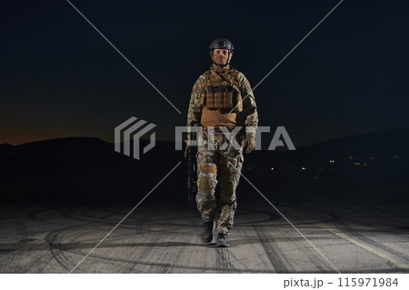 A professional soldier in full military gear striding through the dark night as he embarks on a perilous military mission 115971984