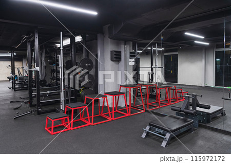 An empty modern gymnasium with a variety of equipment, offering a spacious, functional, and well-equipped training facility for workouts, fitness, and strength training 115972172