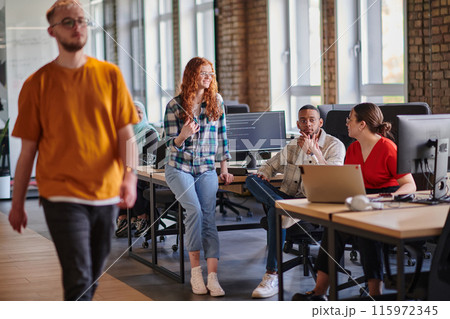 A diverse group of young business individuals congregates in a modern startup coworking center, embodying collaborative innovation and a dynamic atmosphere. 115972345