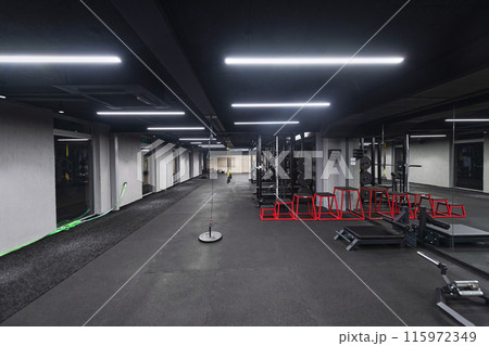 An empty modern gymnasium with a variety of equipment, offering a spacious, functional, and well-equipped training facility for workouts, fitness, and strength training 115972349