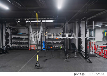An empty modern gymnasium with a variety of equipment, offering a spacious, functional, and well-equipped training facility for workouts, fitness, and strength training 115972484