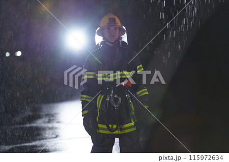 A determined female firefighter in a professional uniform striding through the dangerous, rainy night on a daring rescue mission, showcasing her unwavering bravery and commitment to saving lives. A determined female firefighter in a professional uniform striding through the dangerous, rainy night on a daring rescue mission, showcasing her unwavering bravery and commitment to saving lives. 115972634
