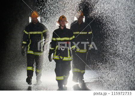A group of professional firefighters marching through the rainy night on a rescue mission, their determined strides and fearless expressions reflecting their unwavering bravery and unwavering 115972733