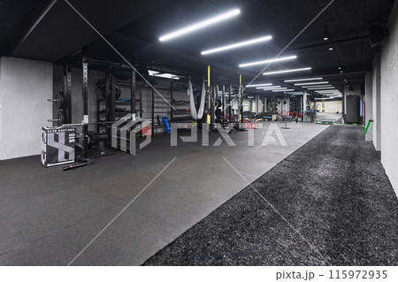An empty modern gymnasium with a variety of equipment, offering a spacious, functional, and well-equipped training facility for workouts, fitness, and strength training 115972935