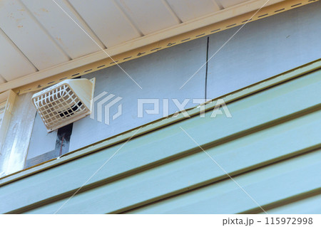 Installing vinyl siding plastic panels on facade wall of new home by an employee 115972998