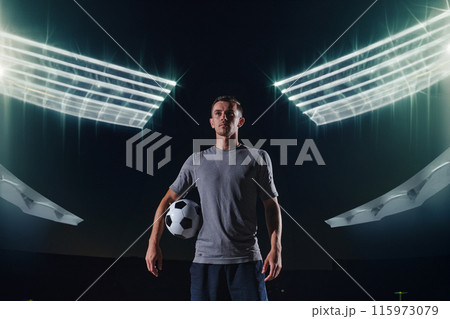 Portrait of a young handsome soccer player man on a street playing with a football ball. 115973079