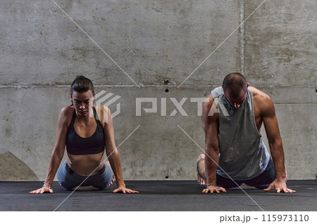 An attractive couple in the gym engaging in various stretching exercises together, showcasing their dedication to fitness, flexibility, and overall well-being. With synchronized movements, they 115973110