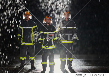 A group of professional firefighters marching through the rainy night on a rescue mission, their determined strides and fearless expressions reflecting their unwavering bravery and unwavering A group of professional firefighters marching through the rainy night on a rescue mission, their determined strides and fearless expressions reflecting their unwavering bravery and unwavering 115973318