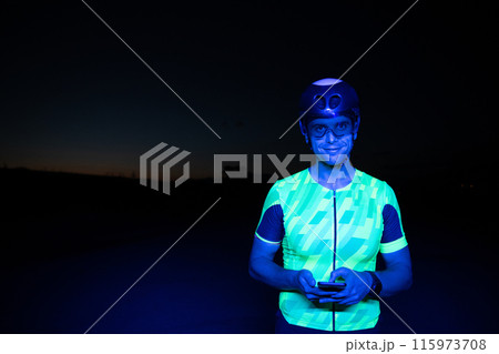 A triathlete using a smartphone while taking a break from a hard night's cycling training A triathlete using a smartphone while taking a break from a hard night's cycling training 115973708
