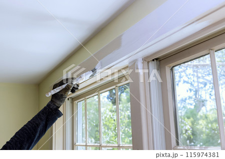 Brush is used to paint window moldings with white paint 115974381