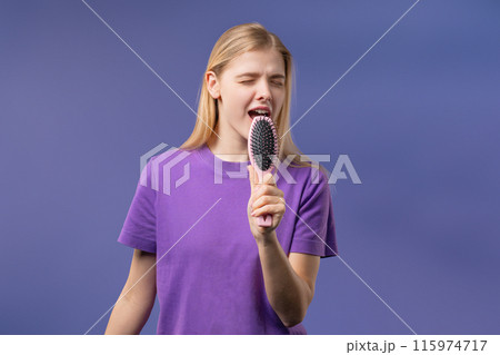 Woman singing, dancing with hair brush instead microphone on Violet background 115974717