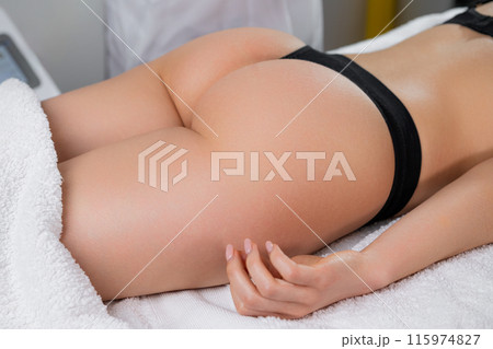 Woman lying on a couch in a massage parlor. Close up woman buttocks in the black lingerie Woman lying on a couch in a massage parlor. Close up woman buttocks in the black lingerie 115974827