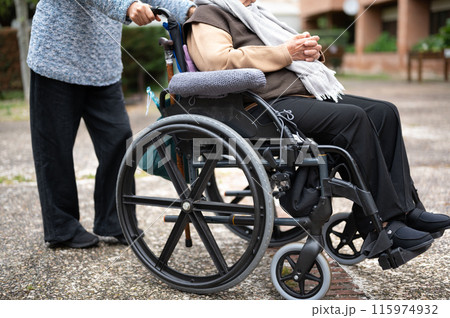 Elderly woman in wheel chair spending time with her daughter in the garden of nursing home 115974932