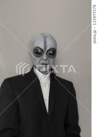 Portrait Of Alien Wearing Suit Gray Background. World UFO Day. Extra Terrestrial Being, Unidentified Flying Objects. Vertical Plane. Grey Humanoid. Portrait Of Alien Wearing Suit Gray Background. World UFO Day. Extra Terrestrial Being, Unidentified Flying Objects. Vertical Plane. Grey Humanoid. 115975578