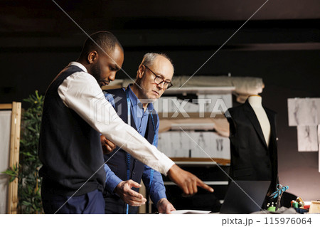 Fashion designers looking online for inspiration, trying to come up with artistic creative haute couture sartorial collection. Teamworking couturiers brainstorming upcoming menswear assortment 115976064