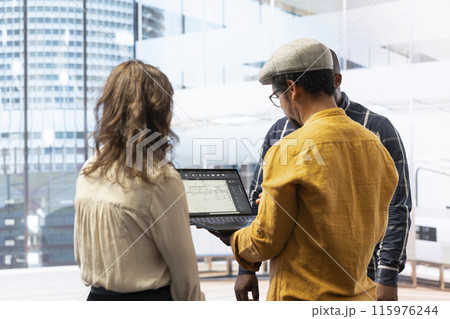 Corporate clients evaluating an investment opportunity in real estate, reviewing architectural blueprints and discussing the best strategies for office relocation and creative development. 115976244