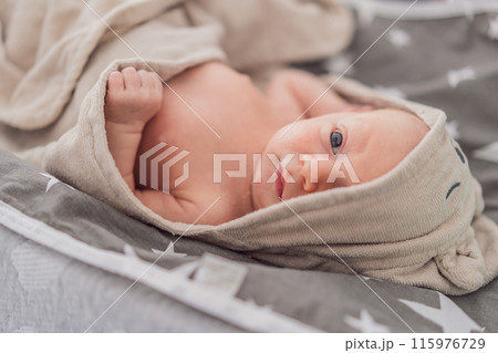 Baby after shower wrapped in a towel. This adorable moment captures the freshness and comfort of a clean baby, highlighting the tender care and love in the daily routine 115976729