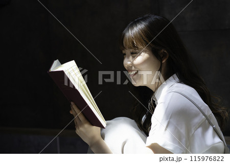 日差しが差し込む部屋で本を読む女性 日差しが差し込む部屋で本を読む女性 115976822