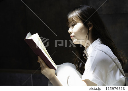 日差しが差し込む部屋で本を読む女性 115976828
