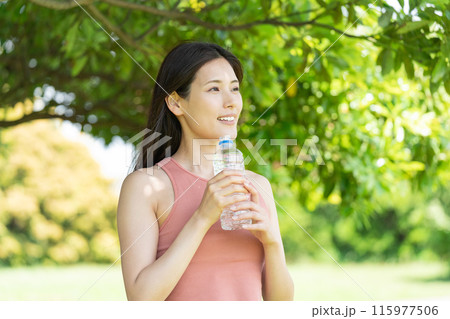 緑豊かな公園で水分補給をする女性（屋外ポートレート、休憩、リラックス） 115977506