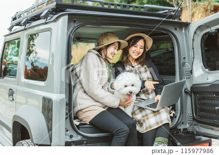 愛犬・ペットと一緒にドライブするアウトドアファッションの女性・友達・親友 115977986