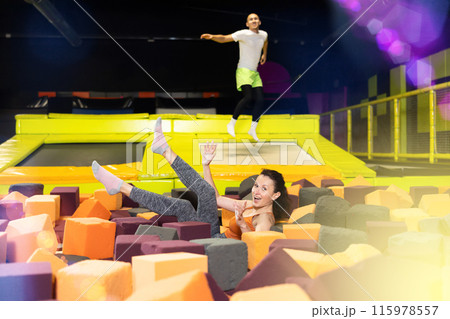 Woman laughing while landing in foam pit at trampoline park Woman laughing while landing in foam pit at trampoline park 115978557
