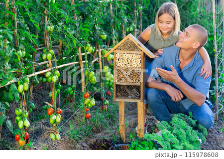 Father and little daughter are happy with the made hotel for insects 115978608