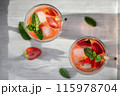 Summer refreshing homemade cocktail with strawberries and mint on the table in a bright kitchen 115978704