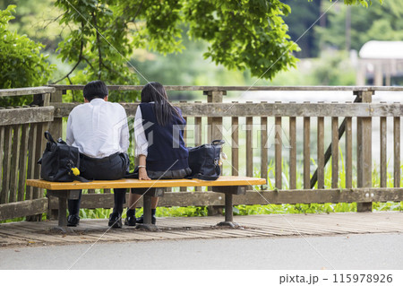 公園のベンチに座る仲良し高校生男女 公園のベンチに座る仲良し高校生男女 115978926
