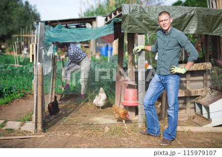 Confident male smallholding owner standing near hen house 115979107