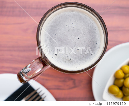 Glass of beer with foamy head served with green olives 115979120