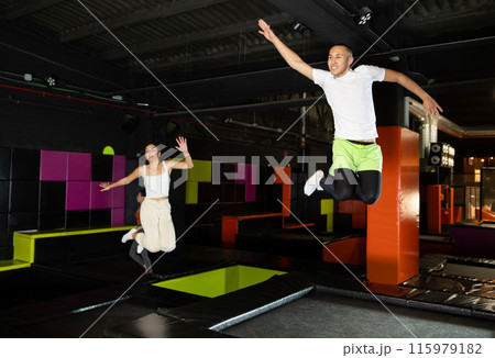Emotional man jumping vertical and flying in trampoline sport center indoors 115979182