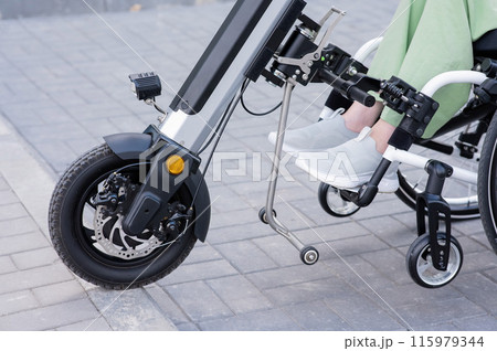 A faceless woman in a wheelchair with an assistive device for manual control. Electric handbike. A faceless woman in a wheelchair with an assistive device for manual control. Electric handbike. 115979344