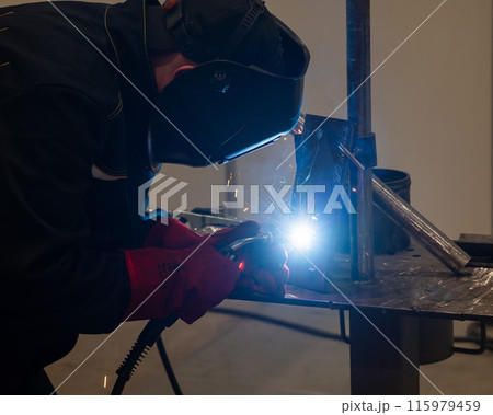 Competitions among welders. A man in a protective mask is welding. Competitions among welders. A man in a protective mask is welding. 115979459