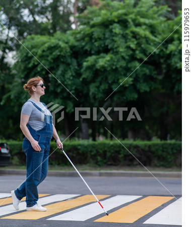 Blind pregnant woman crosses the road at a crosswalk with a cane. Blind pregnant woman crosses the road at a crosswalk with a cane. 115979653