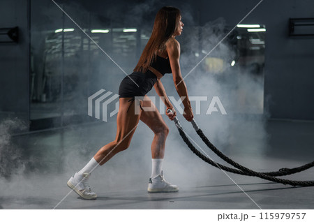 Caucasian woman doing exercise with ropes. Circuit training in the gym. Caucasian woman doing exercise with ropes. Circuit training in the gym. 115979757
